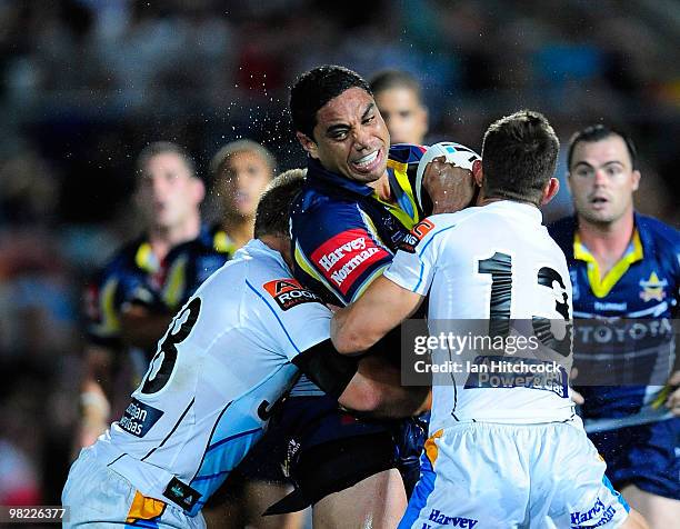 Willie Tonga of the Cowboys is tackled by Ashley Harrison and Michael Henderson of the Titans during the round four NRL match between the North...