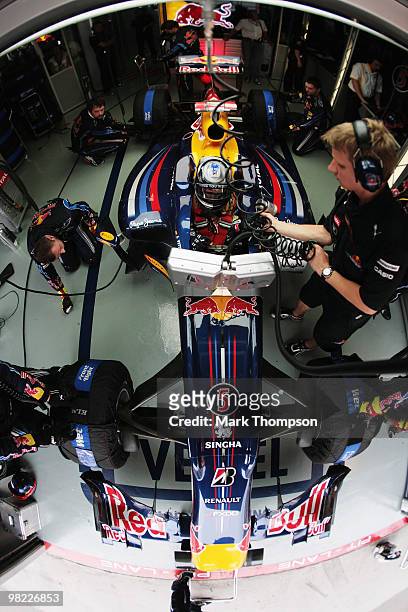 Sebastian Vettel of Germany and Red Bull Racing and his trainer Tommi Parmakoski are seen in their team garage during qualifying for the Malaysian...