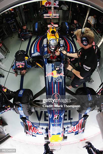 Sebastian Vettel of Germany and Red Bull Racing and his trainer Tommi Parmakoski are seen in their team garage during qualifying for the Malaysian...