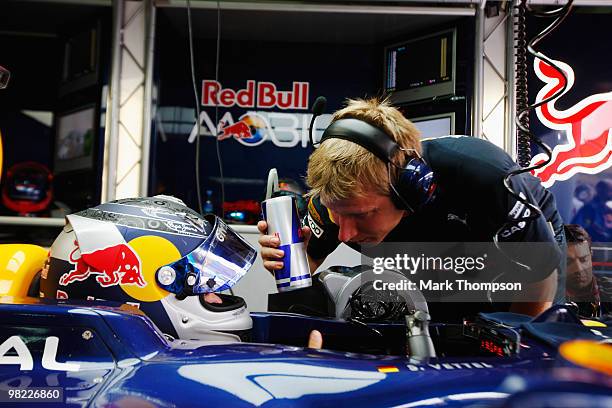 Sebastian Vettel of Germany and Red Bull Racing and his trainer Tommi Parmakoski are seen in their team garage during qualifying for the Malaysian...