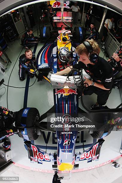 Sebastian Vettel of Germany and Red Bull Racing and his trainer Tommi Parmakoski are seen in their team garage during qualifying for the Malaysian...