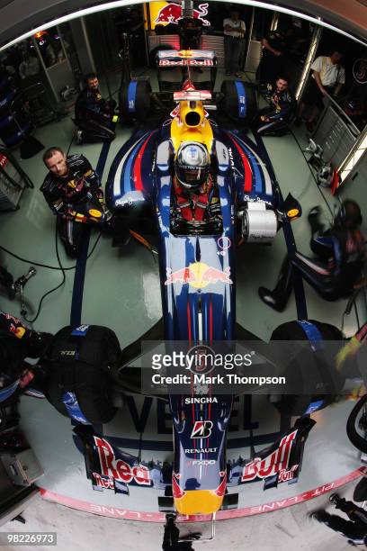 Mechanics work on the car of Sebastian Vettel of Germany and Red Bull Racing in their team garage during qualifying for the Malaysian Formula One...