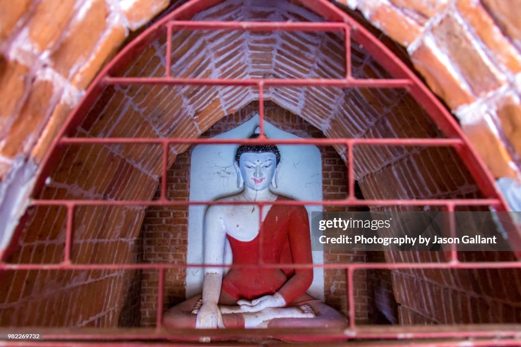 Buddha statue behind bars inside a temple in Bagan, Myanmar.