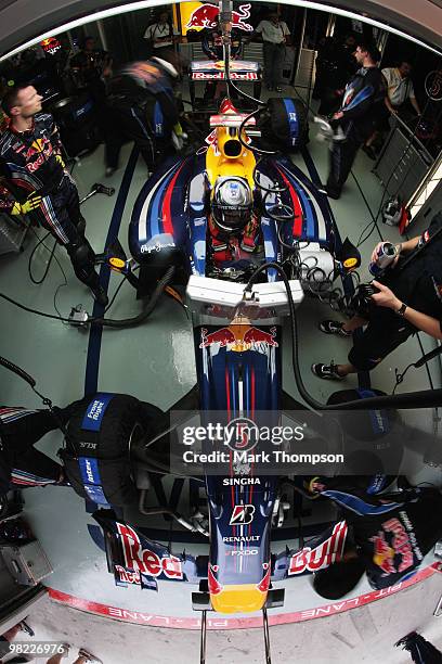 Mechanics work on the car of Sebastian Vettel of Germany and Red Bull Racing in their team garage during qualifying for the Malaysian Formula One...