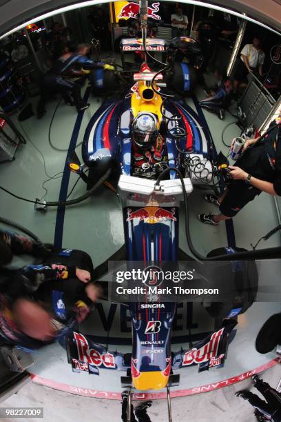 Mechanics work on the car of Sebastian Vettel of Germany and Red Bull Racing in their team garage during qualifying for the Malaysian Formula One...