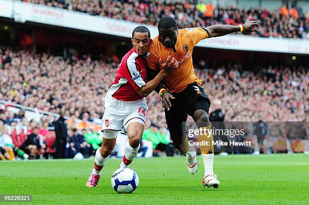 Theo Walcott of Arsenal is challenged by George Elokobi of Wolverhampton Wanderers during the Barclays Premier League match between Arsenal and...