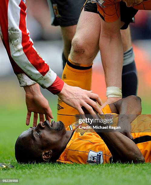 George Boateng of Hull is helped by other players as he lies injured following a kick in the head during the Barclays Premier League match between...