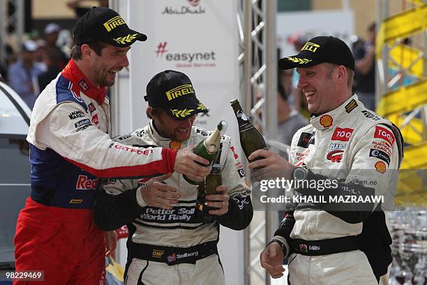 First winner of the FIA world championship in Jordan Frenchman Sebastien Loeb celebrates with third placed Petter Solberg of Norway and his British...