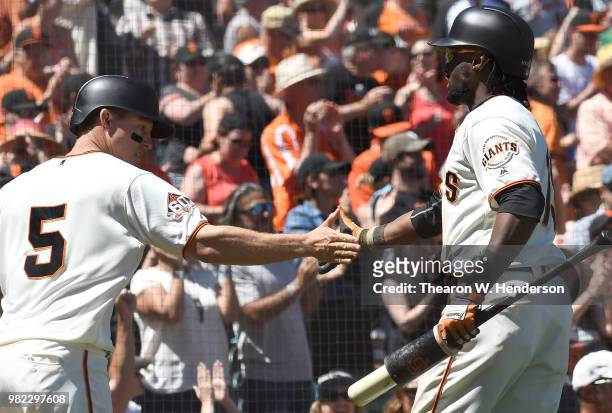 Nick Hundley of the San Francisco Giants is congratulated by Alen Hanson after Hundley scored against the San Diego Padres in the bottom of the...