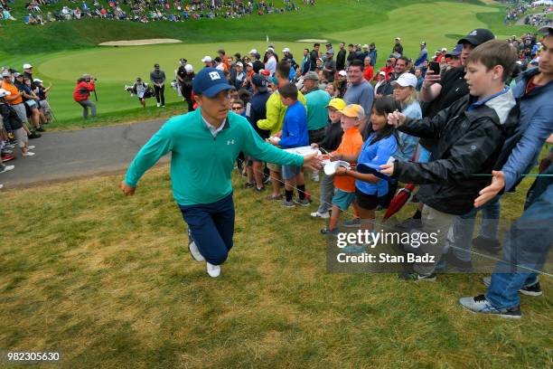 Jordan Spieth slaps hands with fans on the 18th hole during the third round of the Travelers Championship at TPC River Highlands on June 23, 2018 in...