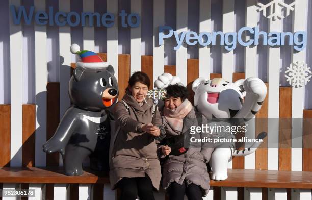 Two visitors taking selfies in front of the Olympic mascots, the white tiger "Soohorang" and the bear "Bandabi", in Pyeongchang, South Korea, 07...