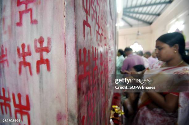 An Indian woman seen drawing the holy sign of Swastika during the Ambubachi festival. The swastika is a geometrical figure and an ancient religious...