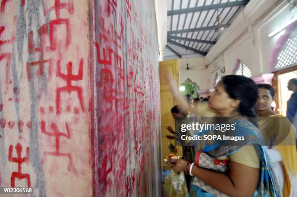 An Indian woman seen drawing the holy sign of Swastika during the Ambubachi festival. The swastika is a geometrical figure and an ancient religious...