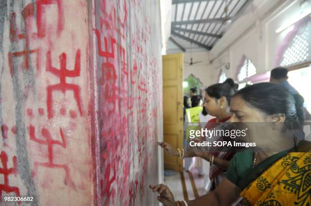 Indian women seen drawing the holy sign of Swastika during the Ambubachi festival. The swastika is a geometrical figure and an ancient religious icon...