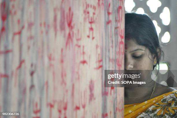 An Indian woman seen praying before the holy sign of Swastika during the Ambubachi festival. The swastika is a geometrical figure and an ancient...