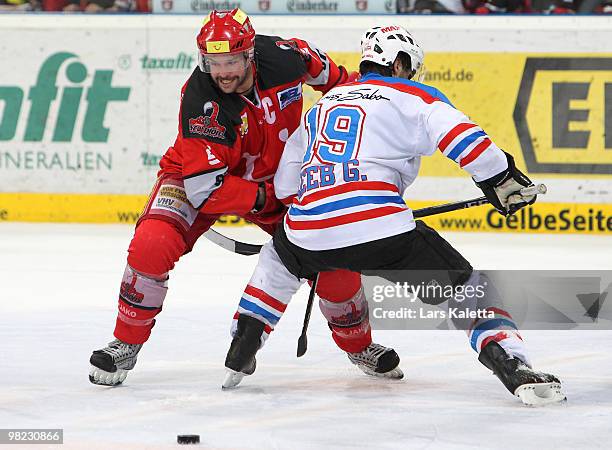 Tino Boos of Hanover and Greg Leeb of Nuernberg battle for the puck during the third DEL quarter final play-off game between Hannover Scorpions and...