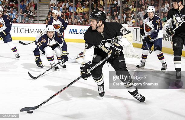 Craig Adams of the Pittsburgh Penguins moves the puck up ice in front of Chris Thorburn of the Atlanta Thrashers on April 3, 2010 at Mellon Arena in...