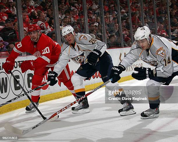 Dustin Boyd of the Nashville Predators, teammate Ryan Suter and Drew Miller of the Detroit Red Wings skate to the loose puck during an NHL game at...