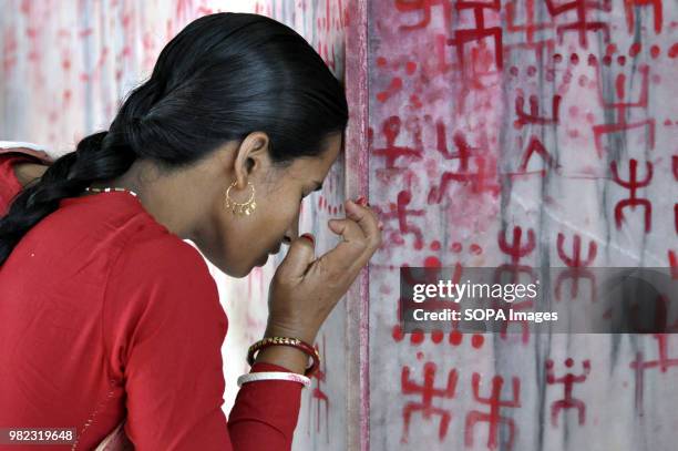 An Indian woman seen praying before the holy sign of Swastika during the Ambubachi festival. The swastika is a geometrical figure and an ancient...