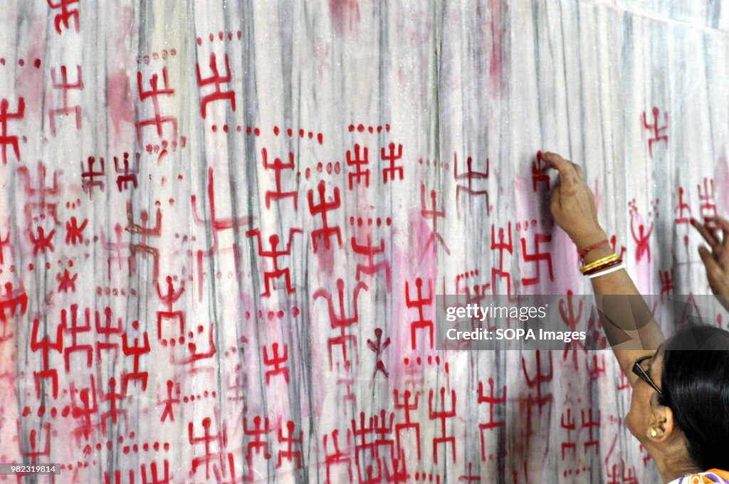 Indian women seen drawing the holy sign of Swastika during...