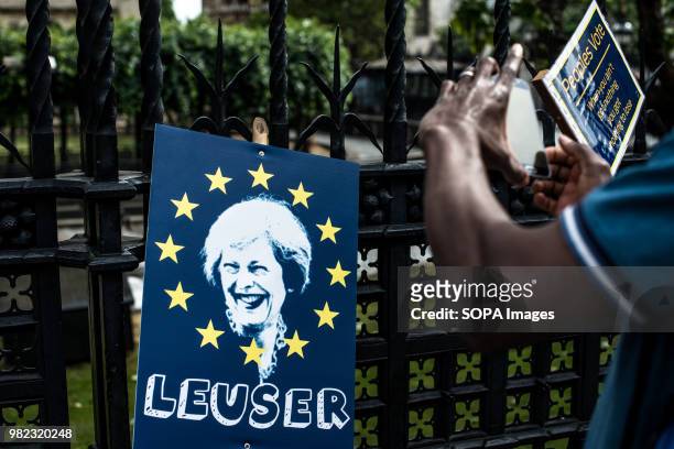 Poster with Theresa May's face and a man taking a picture of it. A coalition of pro-EU groups organized a march to parliament to demand a Peoples...