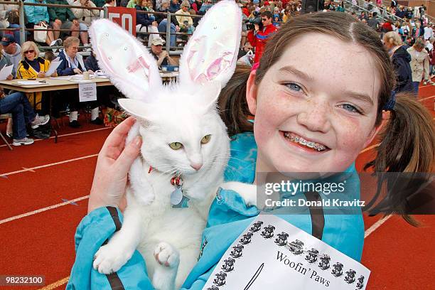 Snowball a white cat wears her Bunny ears while being held by 11 year old, Sabrina as they attend the Woofin' Paws Pet Fashion Show at Carey Stadium...