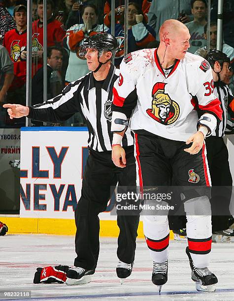 Matt Carkner of the Ottawa Senators is escorted off the ice after being injured during a fight with Trevor Gillies of the New York Islanders on April...