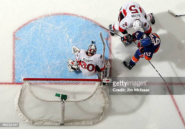 Blake Comeau of the New York Islanders is stopped in the first period by Brian Elliott and Andy Sutton of the Ottawa Senators on April 3, 2010 at...