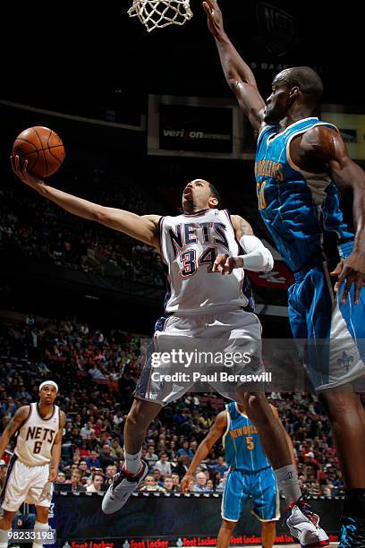 Devin Harris of the New Jersey Nets shoots against Emeka Okafor of the New Orleans Hornets during a game on April 3, 2010 at Izod Center in East...