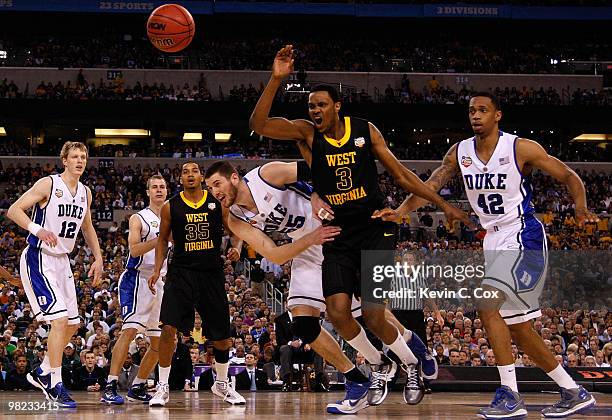 Brian Zoubek and Lance Thomas of the Duke Blue Devils battle for the ball with Devin Ebanks of the West Virginia Mountaineers in the first half...