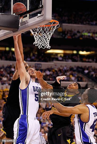 Brian Zoubek of the Duke Blue Devils goes up for a shot between Devin Ebanks and Kevin Jones of the West Virginia Mountaineers in the second half...