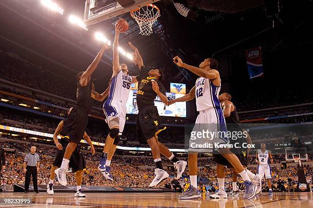 Brian Zoubek of the Duke Blue Devils goes up for a shot between Devin Ebanks and Kevin Jones of the West Virginia Mountaineers in the second half...