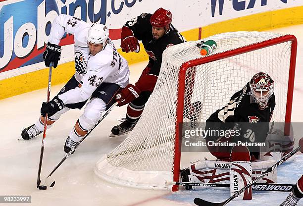 Jason Strudwick of the Edmonton Oilers attempts a wrap around shot on goaltender Ilya Bryzgalov of the Phoenix Coyotes as Adrian Aucoin defends...