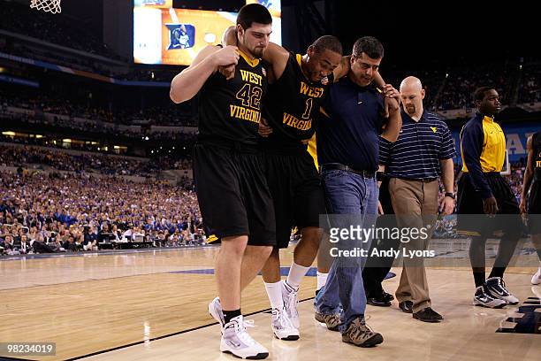 Da'Sean Butler of the West Virginia Mountaineers grimaces as he is helped off the court by Deniz Kilicli after he injured his knee in the second half...