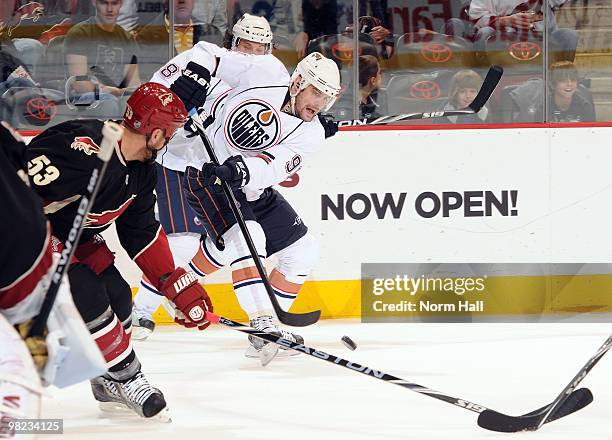 Mike Comri of the Edmonton Oilers shoots the puck over the stick of Derek Morris of the Phoenix Coyotes on April 3, 2010 at Jobing.com Arena in...