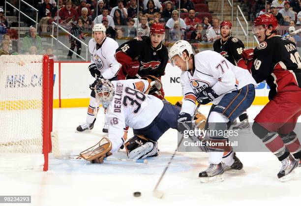 Tom Gilbert of the Edmonton Oilers helps goalie Jeff Deslauriers clear the puck against the Phoenix Coyotes on April 3, 2010 at Jobing.com Arena in...