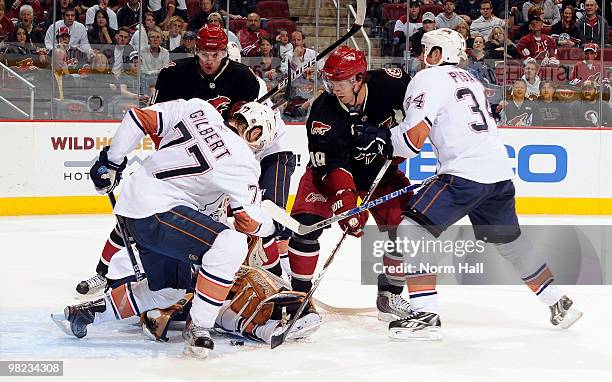 Shane Doan of the Phoenix Coyotes and Tom Gilbert of the Edmonton Oilers scramble for a loose puck on April 3, 2010 at Jobing.com Arena in Glendale,...