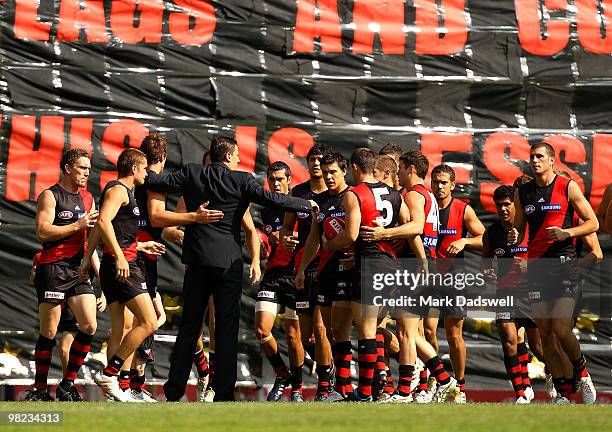 Essendon players run through the banner and are then addressed by former captain Matthew Lloyd during the round two AFL match between the Essendon...