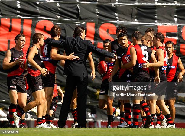 Essendon players run through the banner and are then addressed by former captain Matthew Lloyd during the round two AFL match between the Essendon...