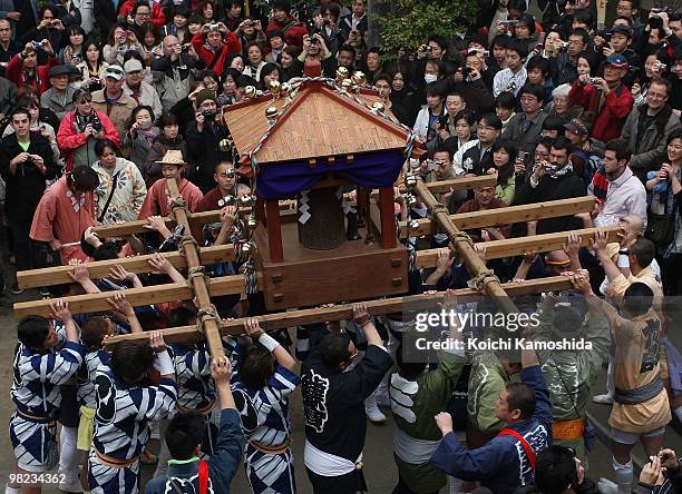 Participants carry a portable shrine with a large gleam black phallus during the Kanamara Festival, or the Utamaro Festival, near Wakamiya Hachimangu...