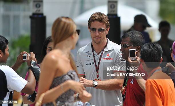 McLaren-Mercedes driver Jenson Button of Britain walks with his girlfriend Jessica Michibata to the paddocks prior to the Formula One's Malaysian...