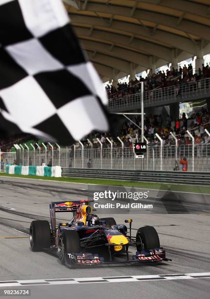 Sebastian Vettel of Germany and Red Bull Racing celebrates as he crosses the finishing line to win the Malaysian Formula One Grand Prix at the Sepang...
