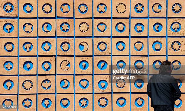 Man watches a "La porta della Bellezza" , 9000 shapes of terracotta made by 2000 children, on a wall of a street in the Sicilian town of Librino, on...