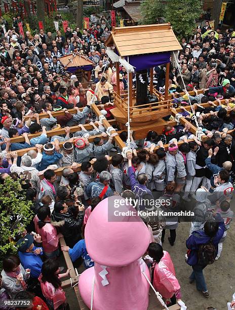 Participants carry a portable shrine with a large pink and a large gleam black phallus during the Kanamara Festival, or the Utamaro Festival, near...