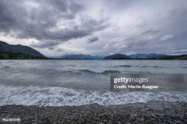 lake wanaka with snowcapped mountains in background and dramatic cloud sky. wanaka, lake wanaka, otago region, south island, new zealand, australasia. - region otago stock pictures, royalty-free photos & images