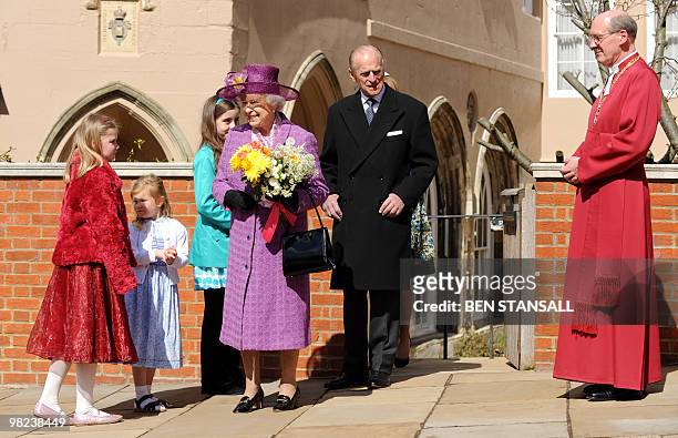 Children give flowers to Britain's Queen Elizabeth II as she leaves with Prince Philip, the Duke of Edinburgh an Easter Sunday church service in...