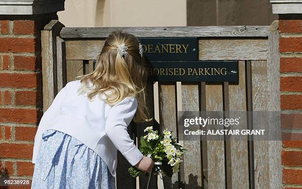 Young girl peaks through a gate as she waits to present a posy to Britain's Queen Elizabeth II after she attended an Easter Sunday church service in...