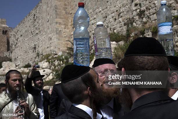 Ultra-Orthodox Jewish Klezemer band members play music and dance with bottles on their heads next to the walls of Jerusalem's old city during...
