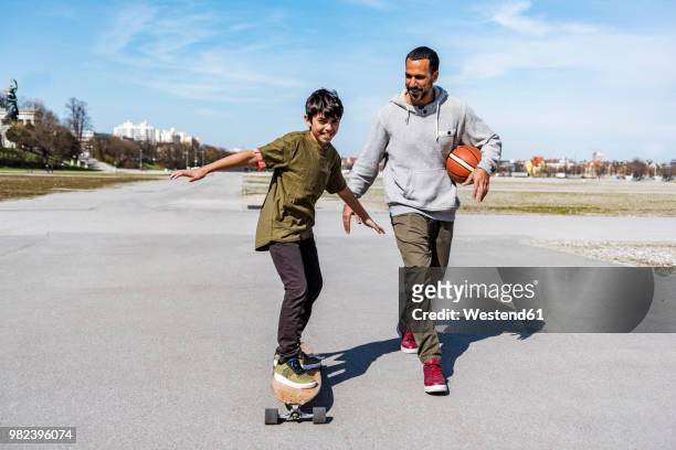 father and son with longboard and basketball outdoors - father longboard stock pictures, royalty-free photos & images