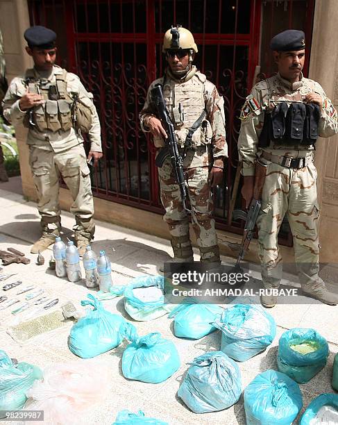 Iraqi soldiers display a cache of weapons and bomb-making equipement discovered inside a building in the Al-Jamia district of west Baghdad on April...